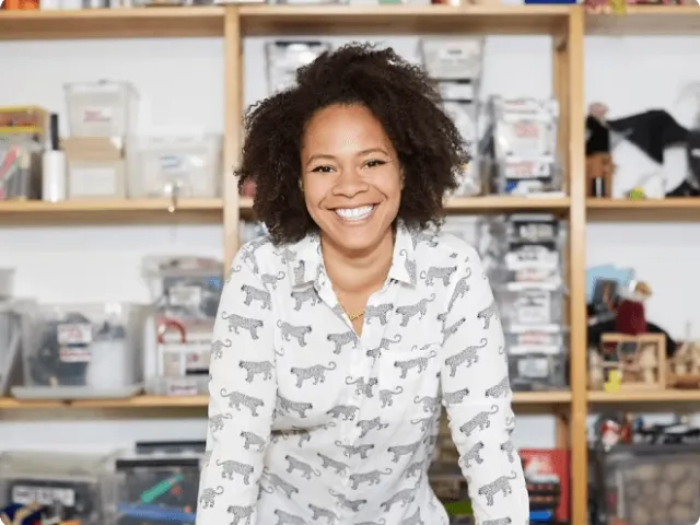 a woman standing in front of a shelf, smiling