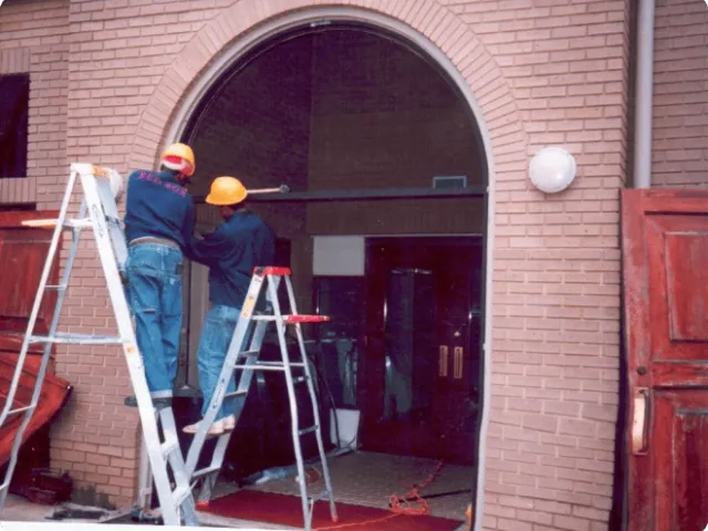 two men on ladders working at the entrance to a building