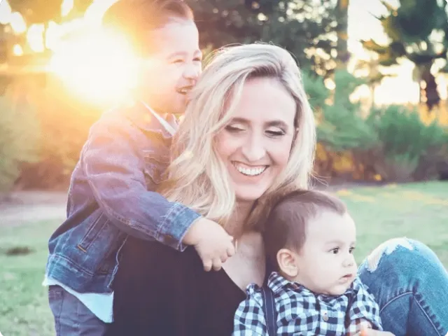 a smiling woman and two children outdoors