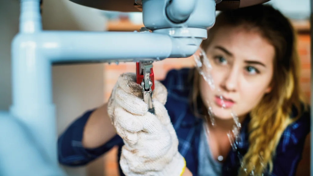 Female lpumber repairing a sink leak