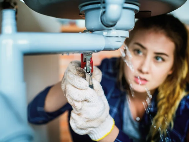 Female lpumber repairing a sink leak