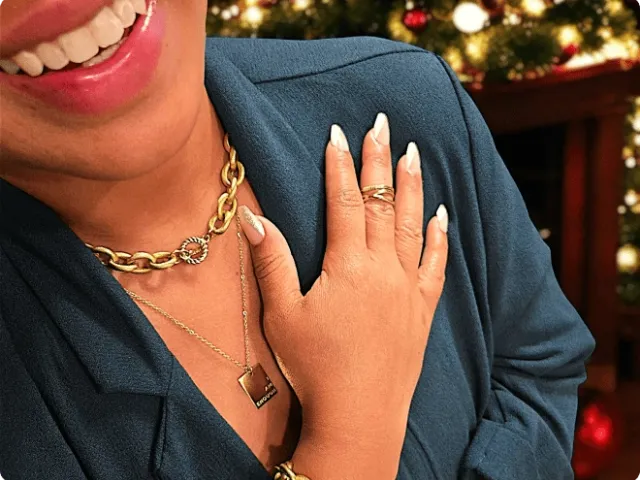 woman smiling and wearing necklaces and a ring