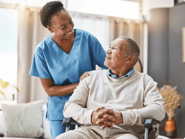 medical professional woman smiling at an older man in a chair
