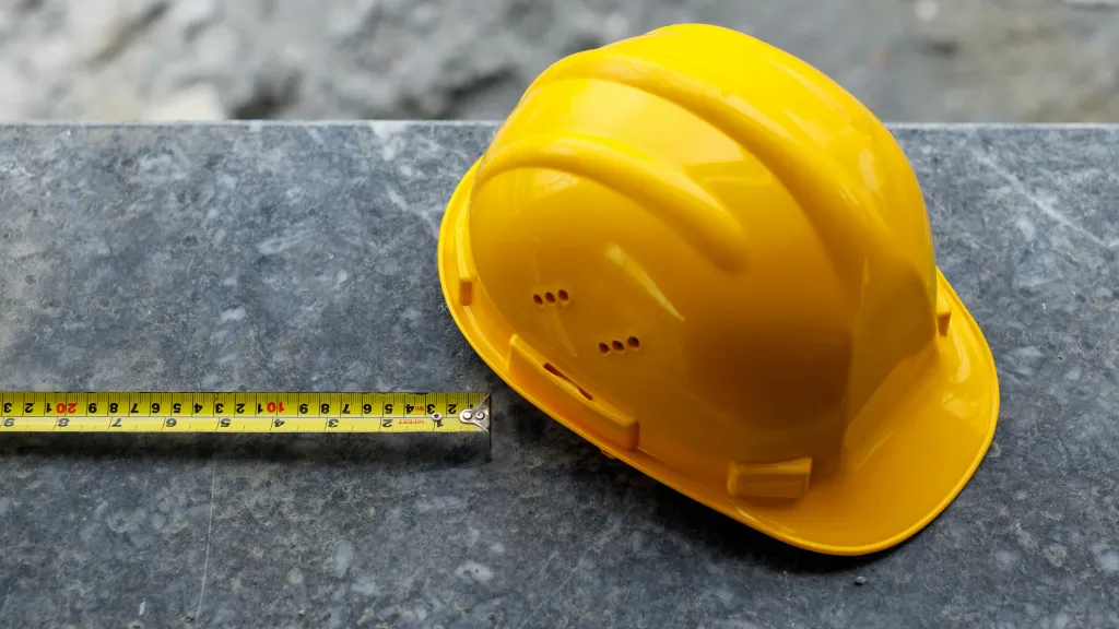 A hard hat next to a tape measure