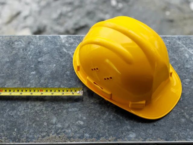A hard hat next to a tape measure