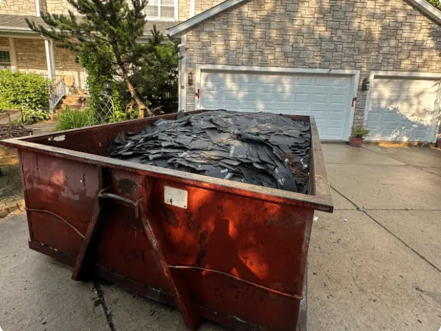 a container full of rock pieces in the driveway of a house