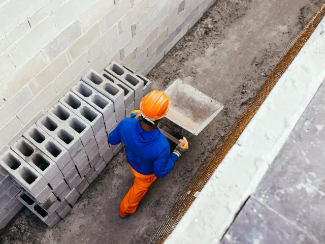 An overhead view of a construction worker in a hard hat pushing a wheelbarrow