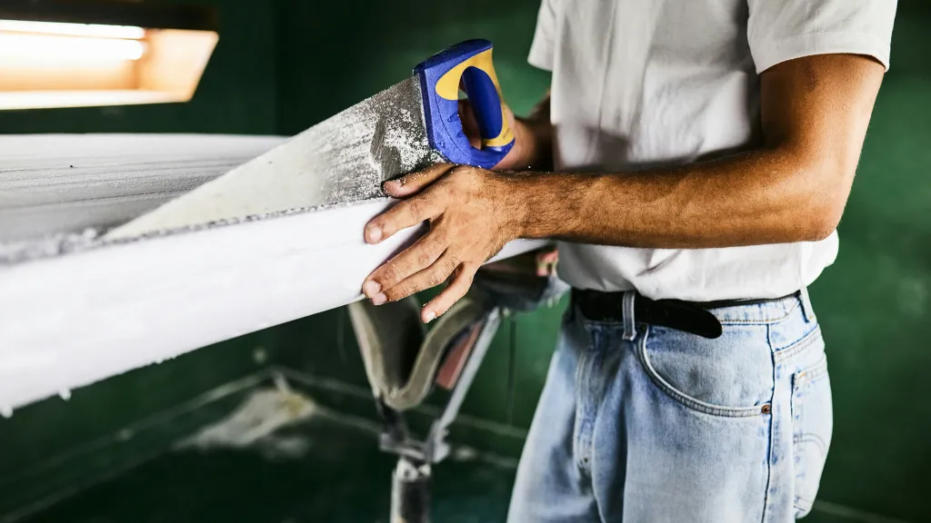 A man cuts a board with a handheld saw