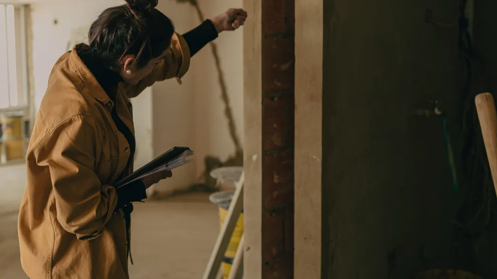 A woman measures a frame in a building