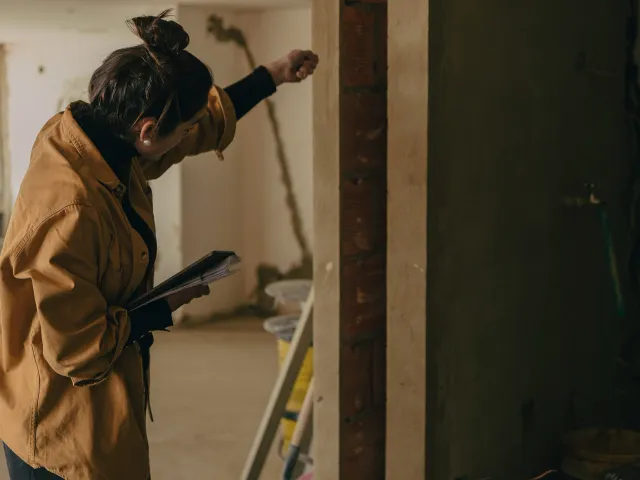 A woman measures a frame in a building