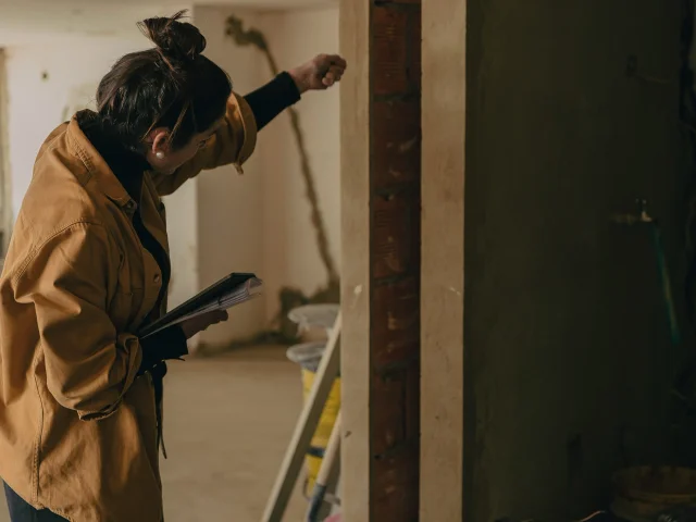A woman measures a frame in a building