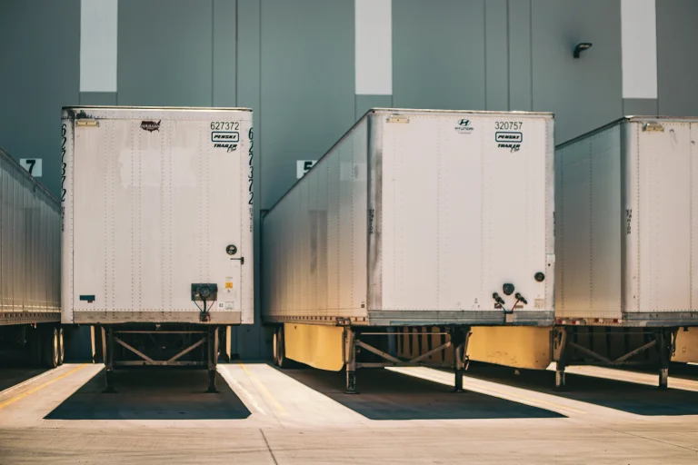 The back of two cargo trucks at a loading dock