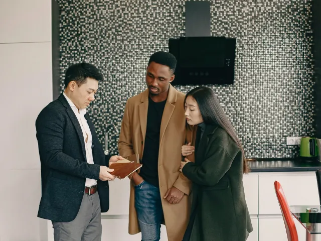 Three people in work clothes look at a document together