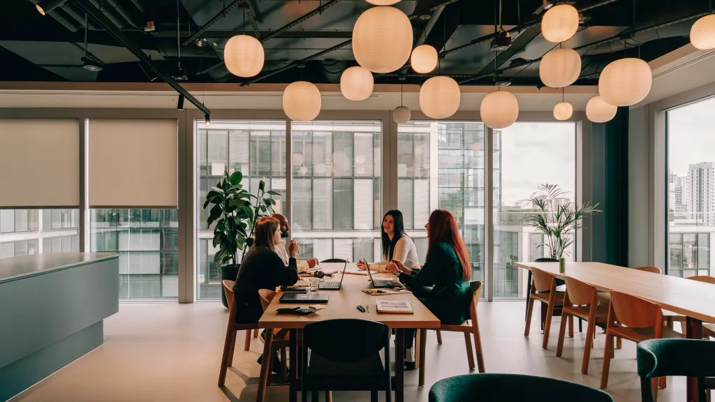 people sitting at a table under round overhead lights