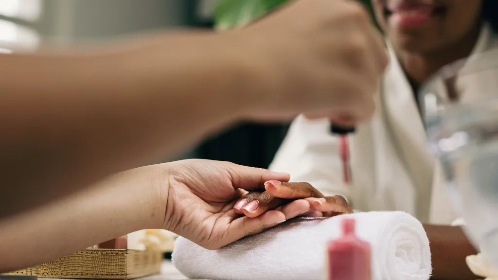 A nail technician prepares to apply polish to a client's nails