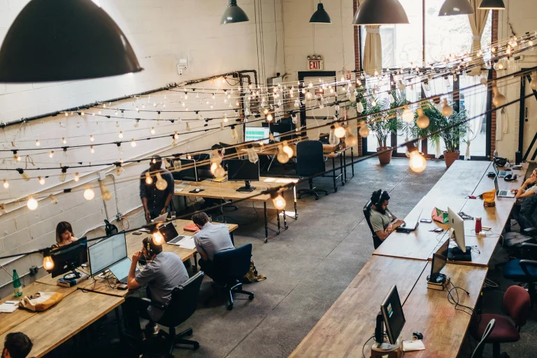 An open workspace with rows of tables and workers on laptops