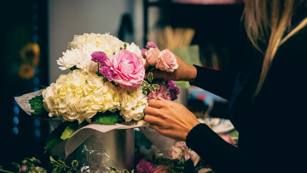 Hands arrange flowers in a vase