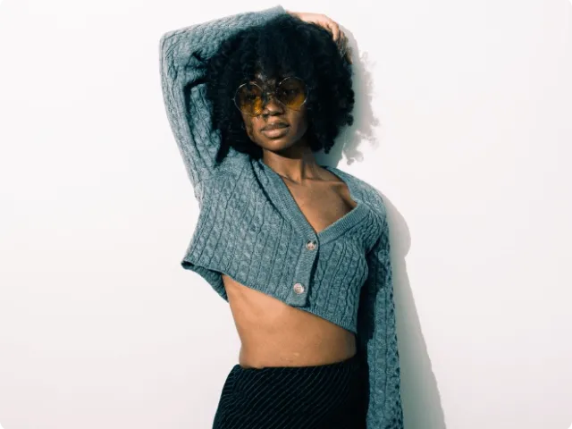 Female model posing with cropped sweater and sunglasses