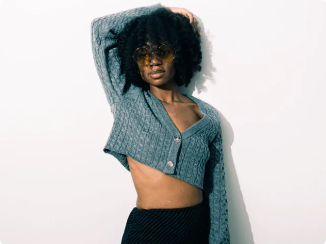 Female model posing with cropped sweater and sunglasses