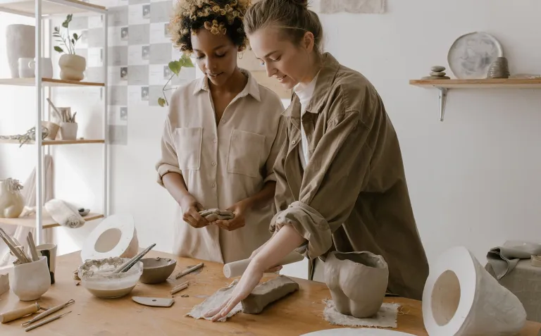 wo small business owners working together on handcrafted ceramics at a workshop table.