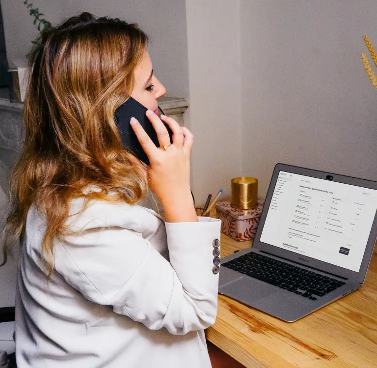 woman on the phone looking at her business finances talking to a business credit coach
