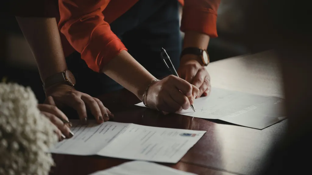 Two people bend over paperwork in a desk