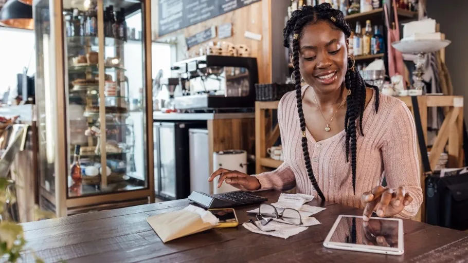 African American Woman small business owner sitting at a table in her coffee shop reviewing her cash flow and credit score