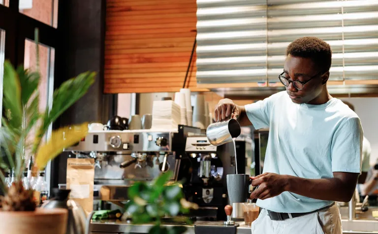 Barista pouring milk into a coffee cup