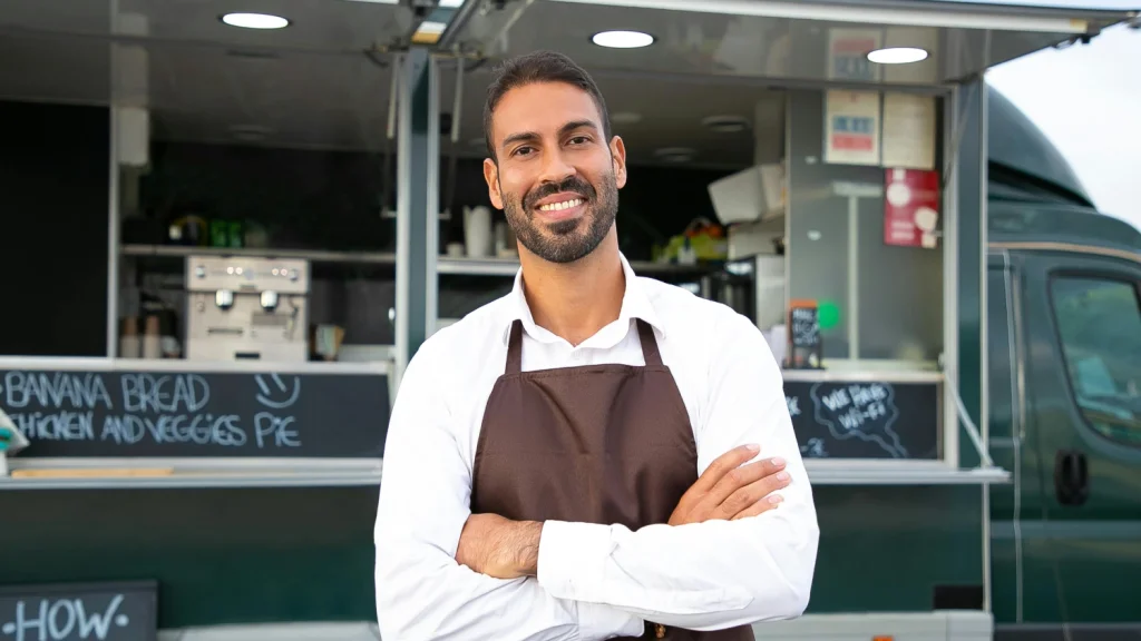 man wearing apron standing in front of a food truck