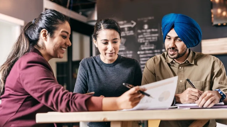 Three small business owners sitting at a table discussing the details of a commission based loan