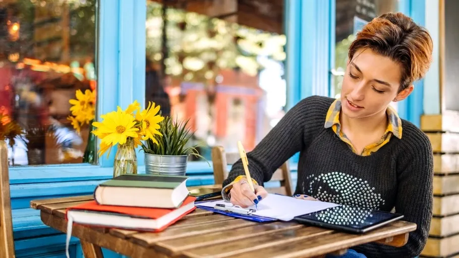Small business owner sitting at a cafe table reviewing her possible tax write offs on a tablet