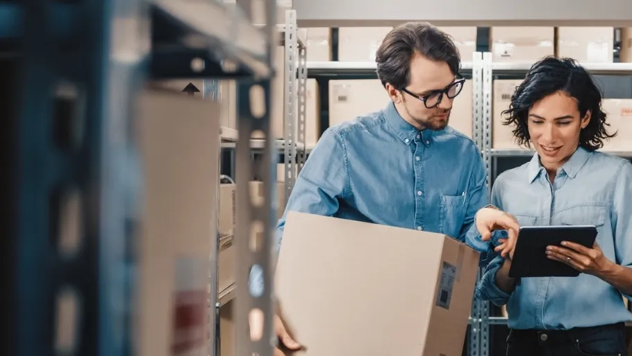 Two small business owners discussing LLc formation while standing in a store room looking at an ipad