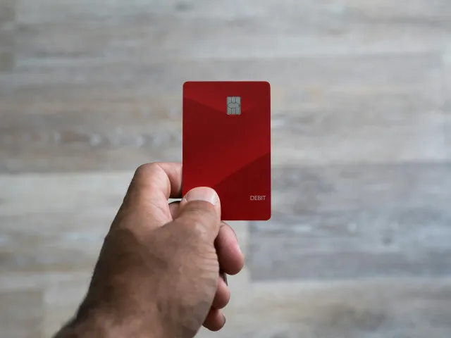 A hand holding a red credit card