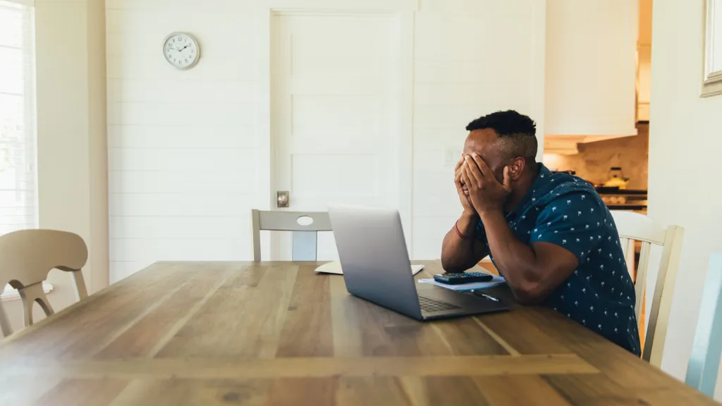Small business owner sitting at a table with a laptop frustrated with tax due dates