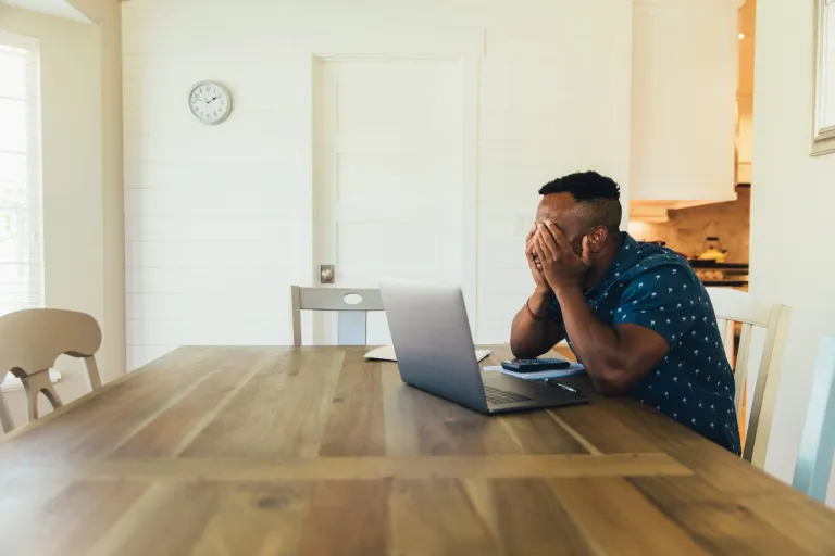 Small business owner sitting at a table with a laptop frustrated with tax due dates