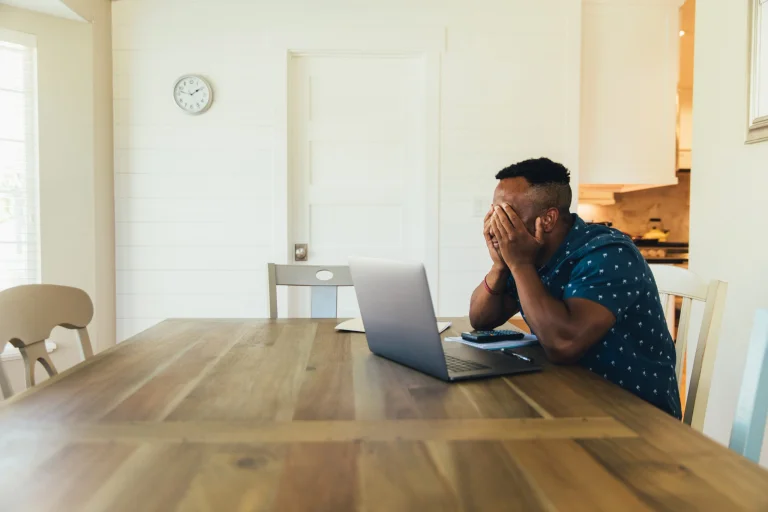 Small business owner sitting at a table with a laptop frustrated with tax due dates
