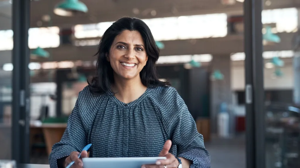 Business owner on tablet facing camera smiling to illustrate article about credit invisibles