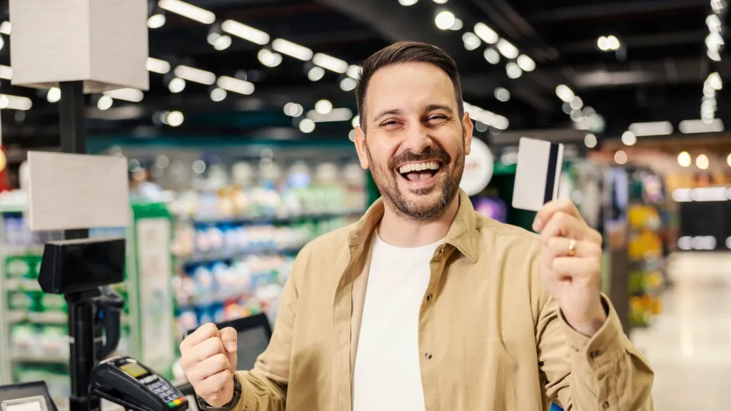 Photo of business owner at cash register holding credit card to represent lower swipe fees