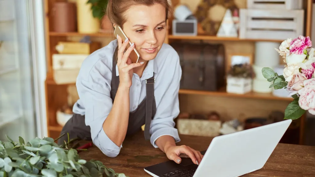 business owner on phone and computer checking into payday loans