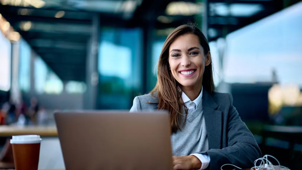 young woman in professional clothing smiling with laptop