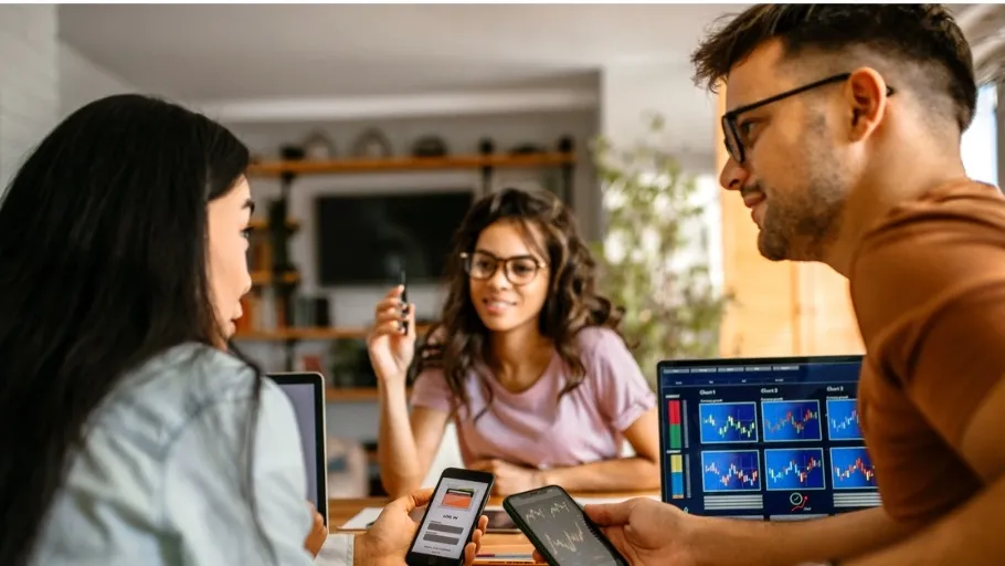 two women and one male small business owners sitting at a table discussing crypto currency