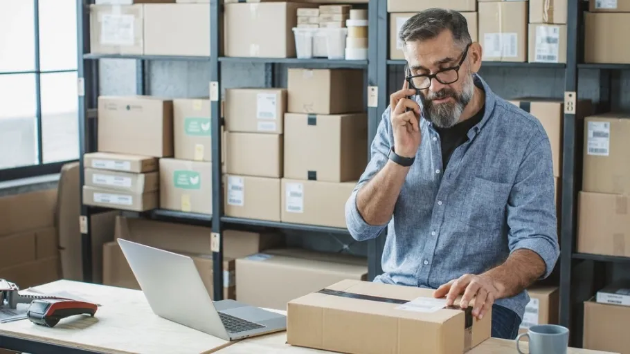 e-commerce small business owner on the phone while packing boxes