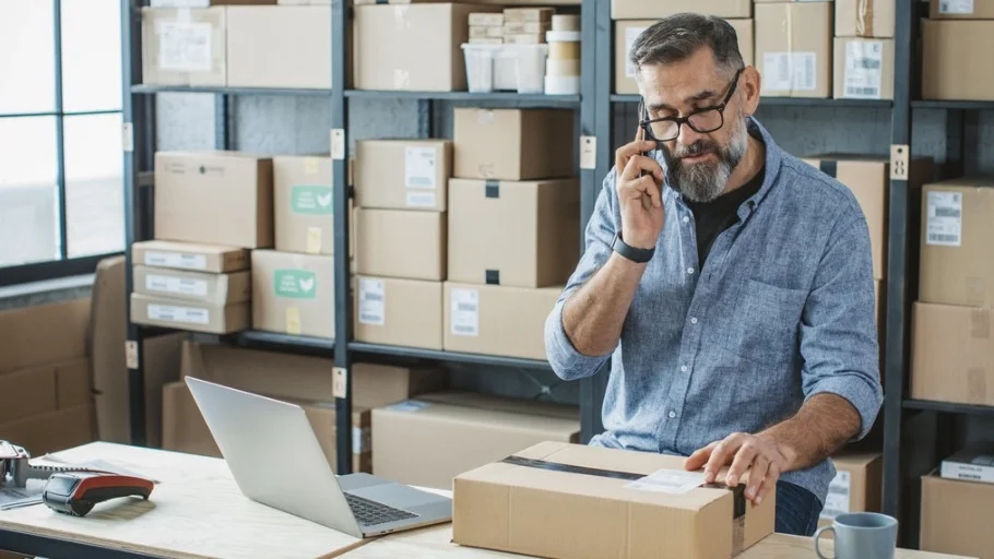 e-commerce small business owner on the phone while packing boxes