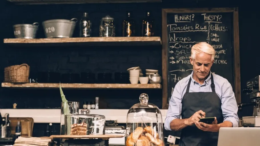 Man behind the counter at his small business doing calculations