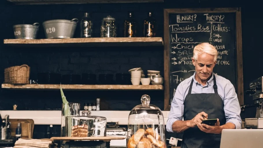 Man behind the counter at his small business doing calculations