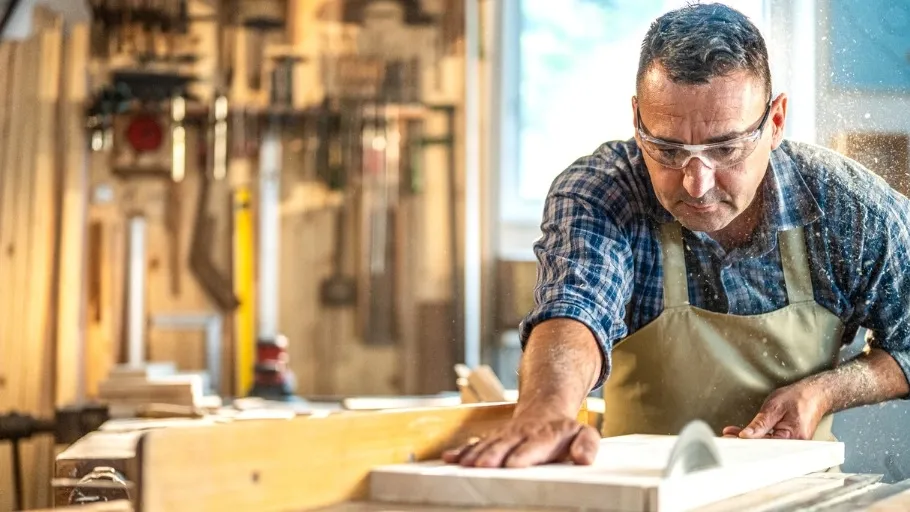 Male Small business owner using a table saw