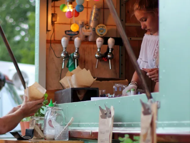 A colorfully-lit food truck with a worker preparing food