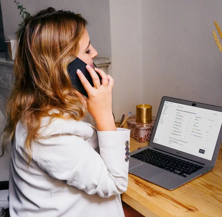 Small business coach speaking on the phone while reviewing loan qualifications on a laptop during a Nav business credit coaching session.