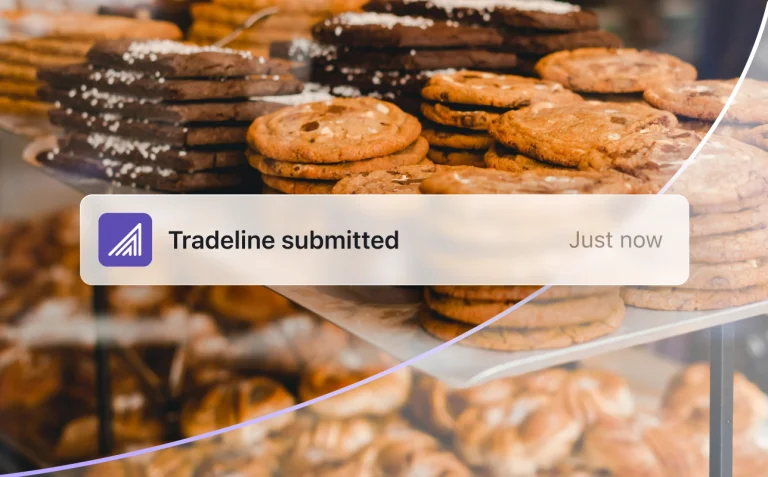 Notification banner confirming tradeline submitted over a bakery display background.