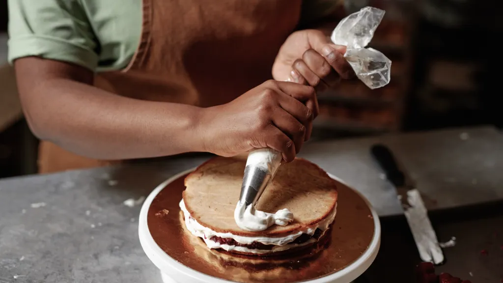 A person squeezes icing to decorate a cake